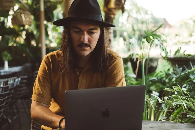 Creator working on a laptop outdoors, planning a multi-platform selling strategy