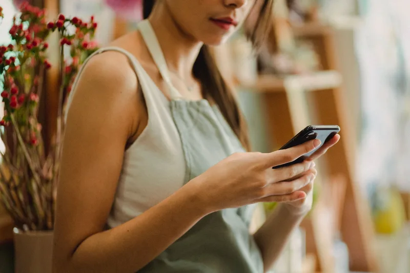 Person checking phone notifications while working in a small shop