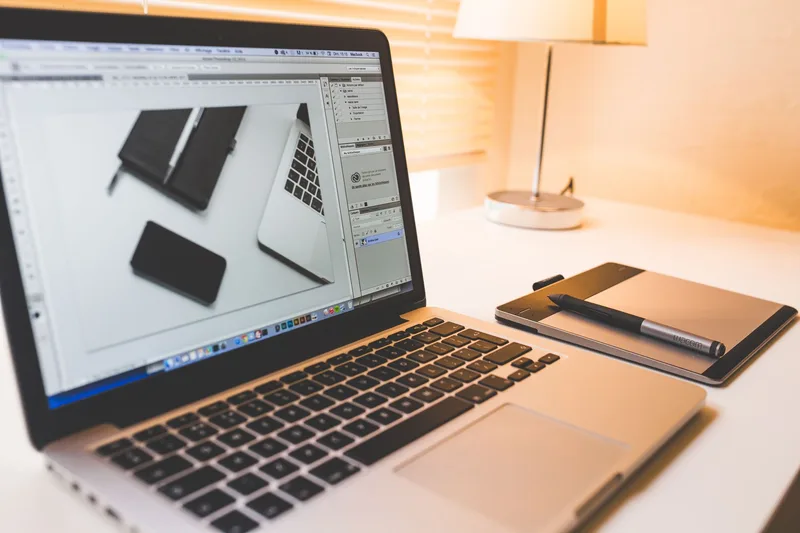 Laptop on a desk with digital pen, representing a creative design workspace