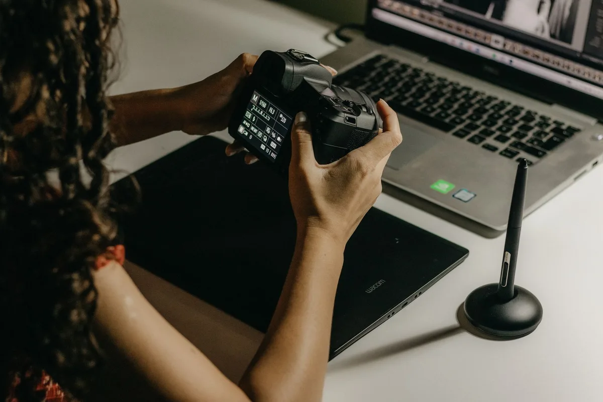 Photographer using a DSLR camera and digital tablet for photo editing on a laptop