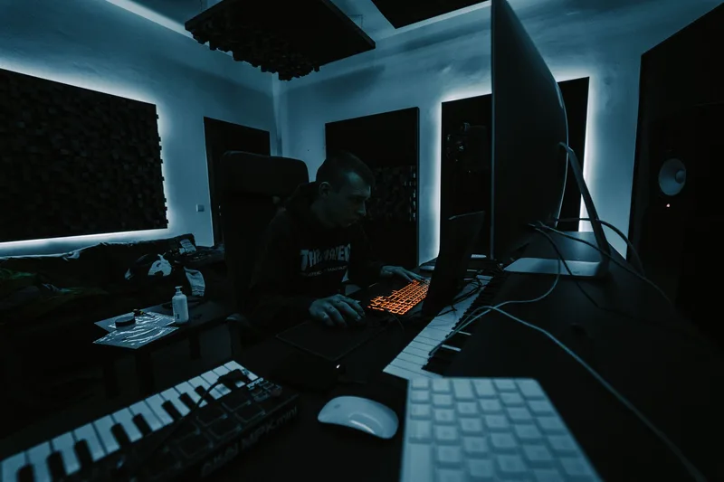 Producer working on a beat with headphones and a MIDI keyboard in a home studio