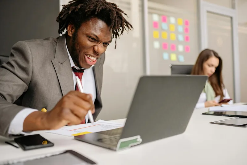 Person sitting at a laptop with a satisfied expression after making a first online sale