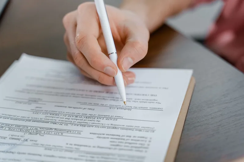 Hand holding a pen signing a document