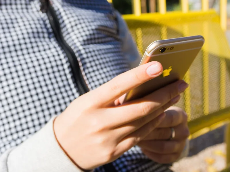 Close-up of a hand holding a smartphone outdoors, representing checking a sale or payout notification